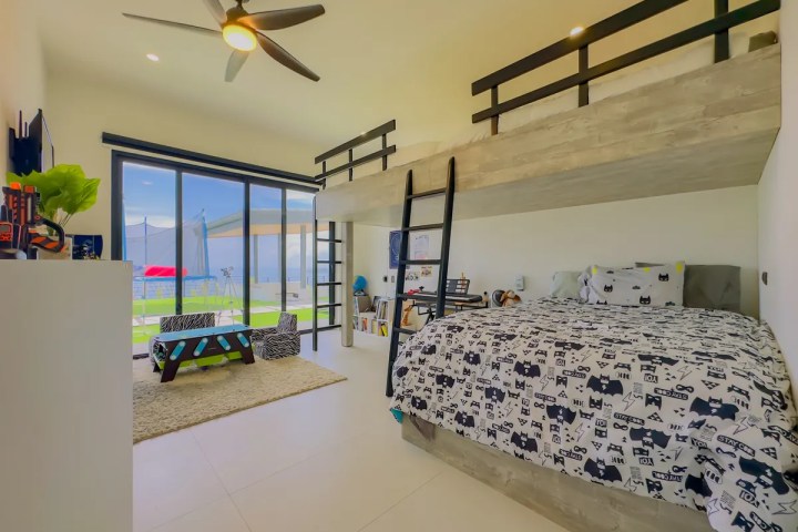 Modern bedroom with a loft bed, black ladder, sliding doors, and playful decor.