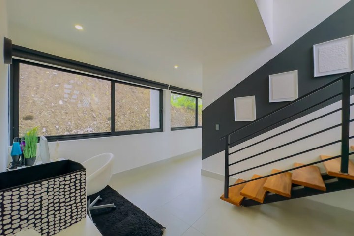 Modern room with large windows, black staircase, and minimalist decor.