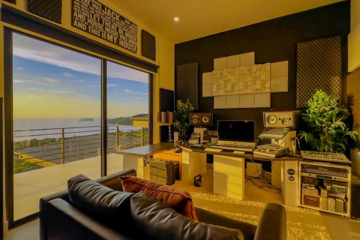 Home studio with large window view of ocean, audio equipment, and sofa.