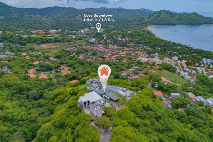 Aerial view of green landscape with marked location and coastal town in the background.