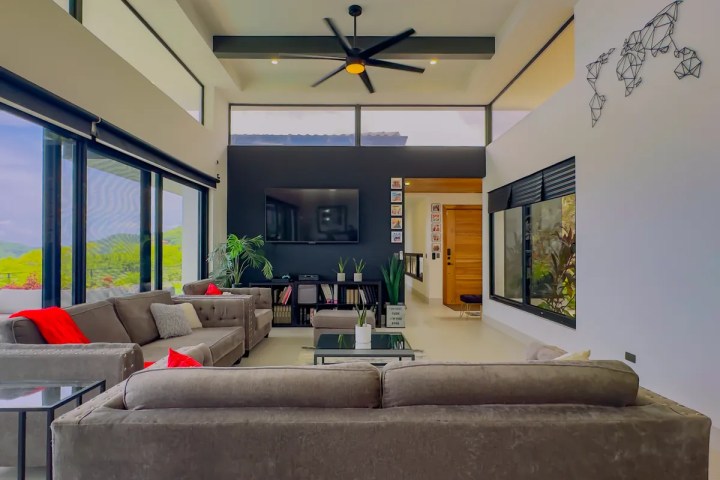 Modern living room with gray sofas, large windows, and geometric wall art.