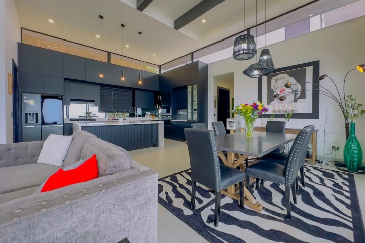 Modern open-plan kitchen and dining area with black and white decor and zebra print rug.