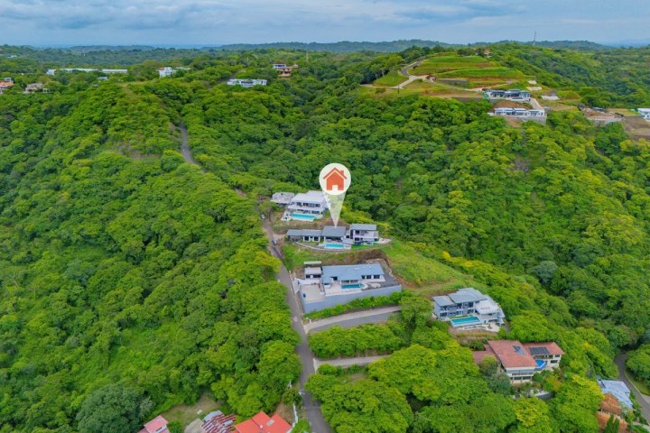 Aerial view of houses surrounded by lush green hills.
