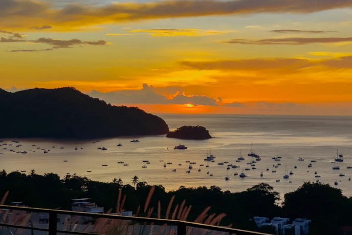 Sunset over bay with boats and distant hills.