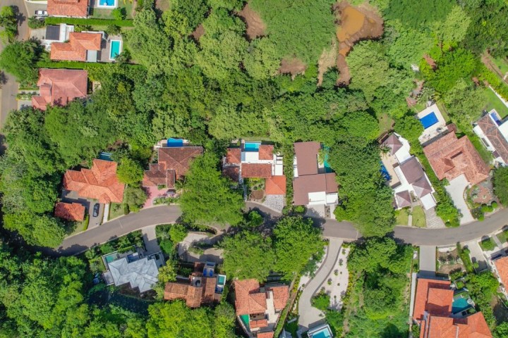 Aerial view of suburban neighborhood with houses, trees, and curved roads.