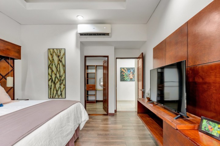 Bedroom with wooden decor, TV, wall art, and air conditioner.