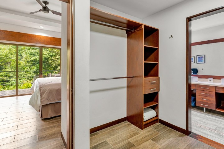 Bedroom with balcony, wooden closet, and modern ensuite bathroom.
