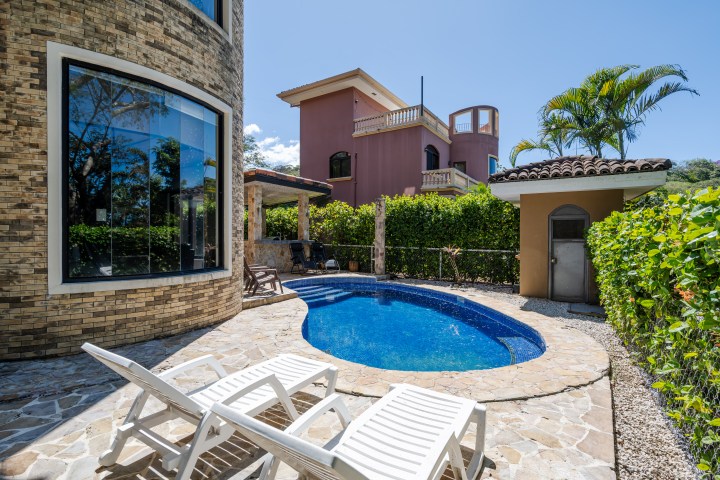 Outdoor pool area with two white lounge chairs and a curved brick building.