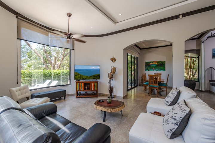 Spacious living room with sofas, TV, and dining area, large windows with garden view.