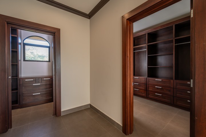 Two wooden walk-in closets with open shelving and drawers seen from a hallway.