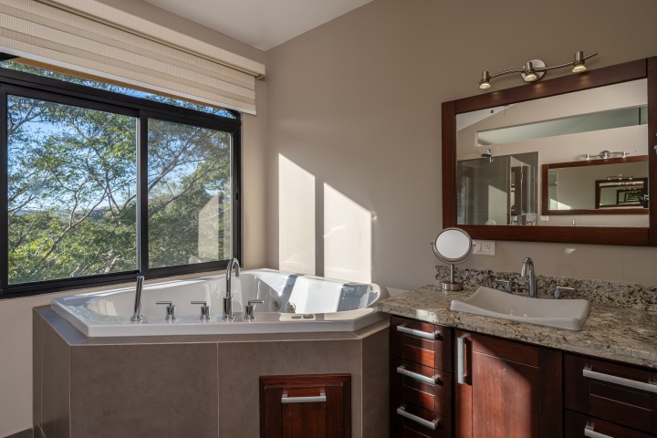 Modern bathroom with a jacuzzi tub, large window, and granite countertop.