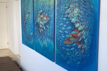 Three-panel blue abstract artwork on a white wall in a modern hallway with track lighting.