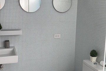 Modern bathroom with circular mirrors, sink, and toilet on tiled walls and floor.