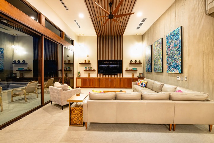 Modern living room with large sectional sofa, artwork, and ceiling fan.