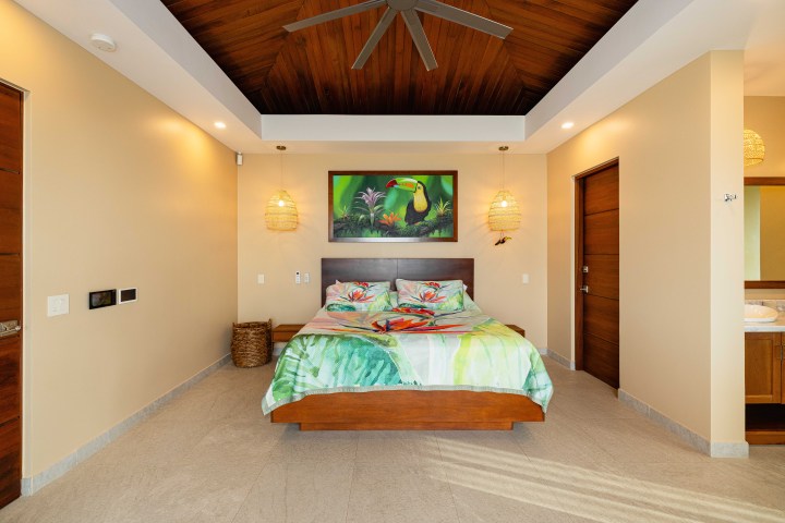 Tropical-themed bedroom with a toucan painting, fan, and wooden accents.