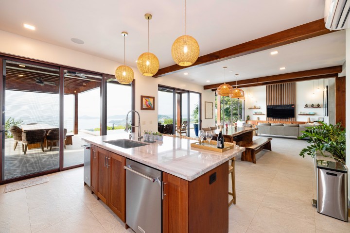 Modern open-plan kitchen and living room with large windows and pendant lights.