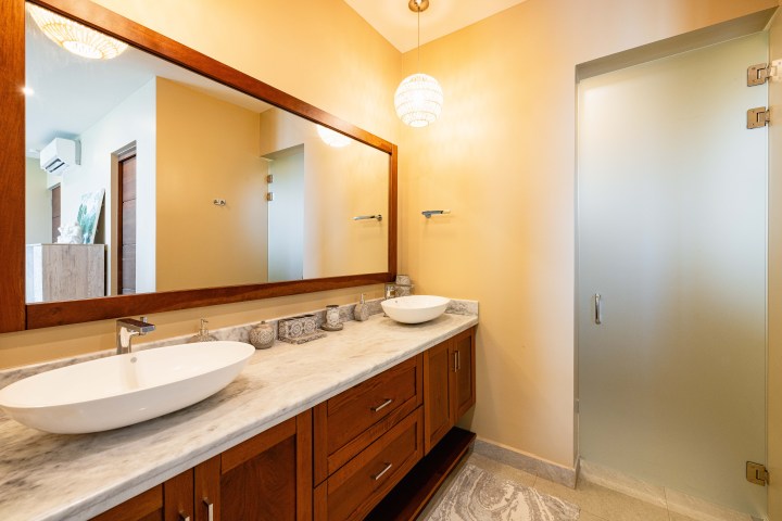 Elegant bathroom with double sinks, large mirror, and frosted glass door.