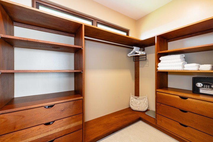 Wooden closet with shelves, drawers, folded towels, and a safe inside.