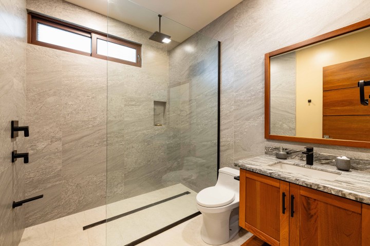 Modern bathroom with glass shower, wooden vanity, and large mirror.