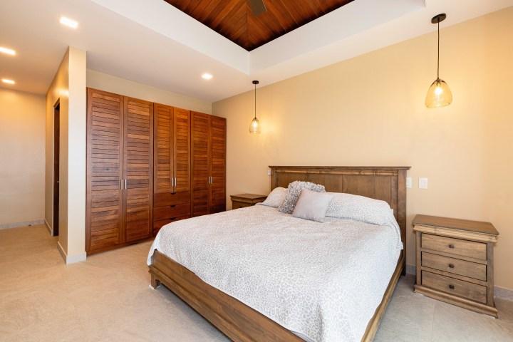 Bedroom with wooden furniture, bed, side tables, and pendant lights.