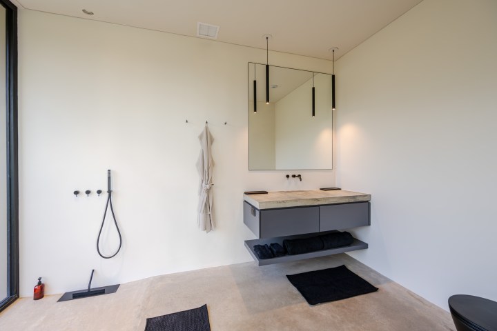 Minimalist bathroom with floating vanity, mirror, and shower with black fixtures.