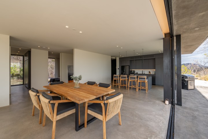 Open-plan kitchen and dining area with wooden table, chairs, and modern appliances.