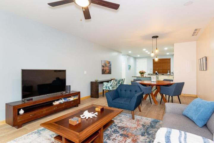 Modern living room with blue chairs, TV, and dining area in open-plan layout.