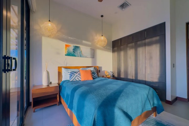 Sunlit bedroom with blue bedding, modern decor, and a large wardrobe.