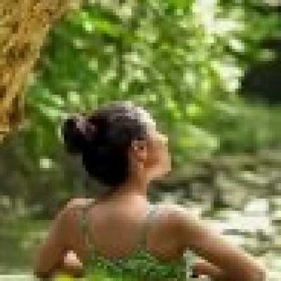 Person in green swimsuit relaxing in a forest river, surrounded by lush greenery.