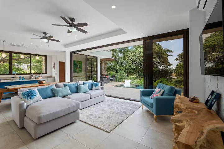 Modern living room with glass doors to a patio, large sofa, blue armchair, and wooden furniture.