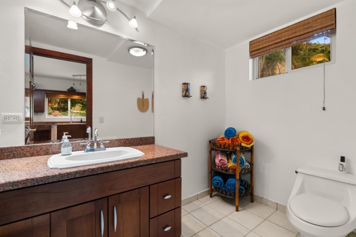 Bathroom with sink, mirror, and stacked colorful towels.