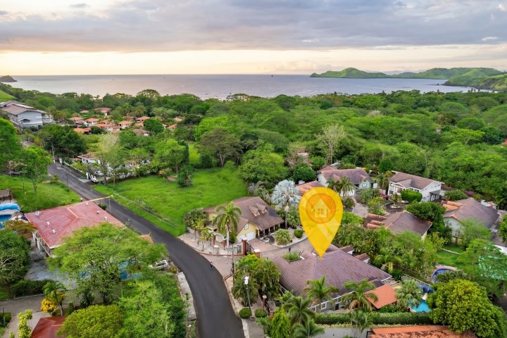 Aerial view of a lush coastal village with a digital location marker.