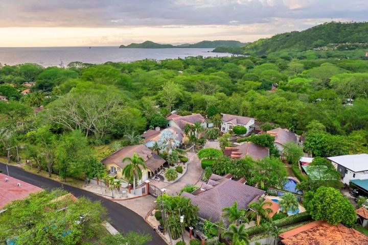 Aerial view of coastal town with lush greenery and ocean in the background.