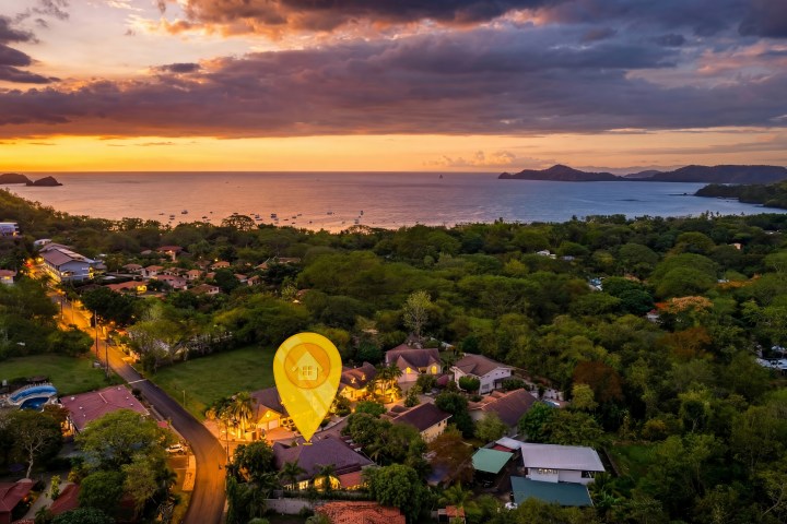 Sunset over coastal town with a location pin marking a house.