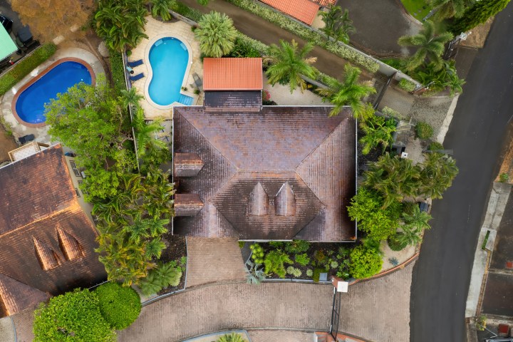 Aerial view of a house with a pool and surrounding greenery.