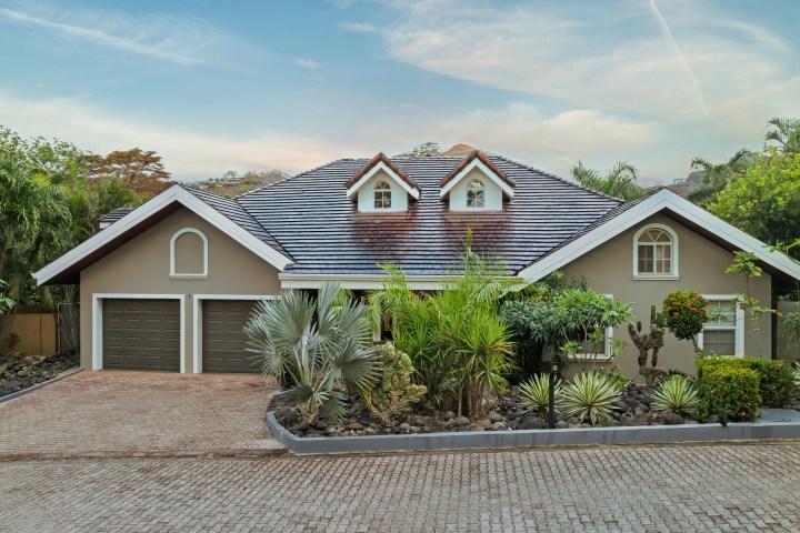 Single-story house with a tiled roof, two dormer windows, and lush front garden.