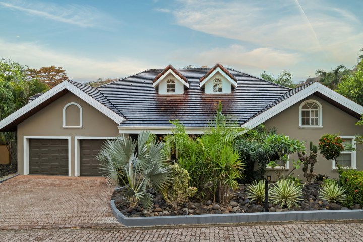 Front view of a suburban house with two garages and a manicured garden.