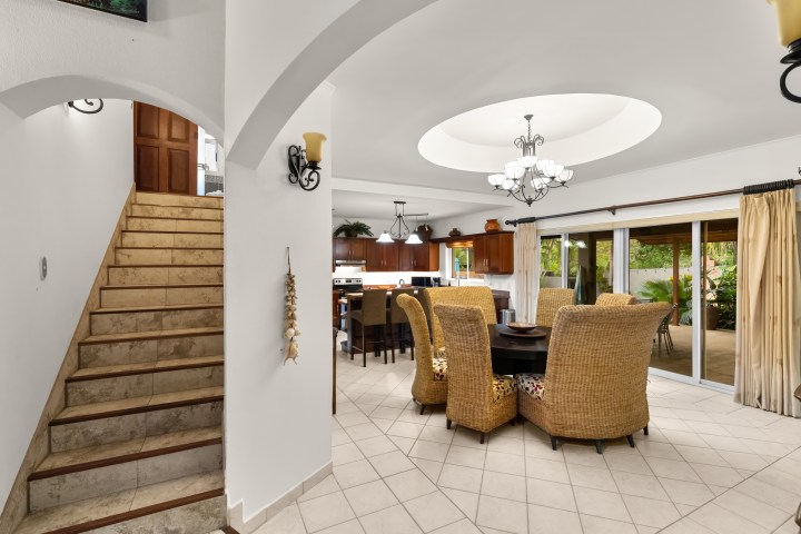 Open dining area with wicker chairs, round table, and view of kitchen and patio.