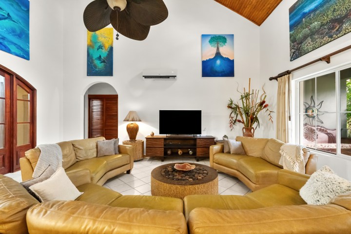 Spacious living room with yellow sofas, art, and a TV.