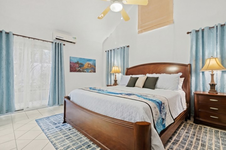 Bright bedroom with a large bed, blue curtains, and two lamps.