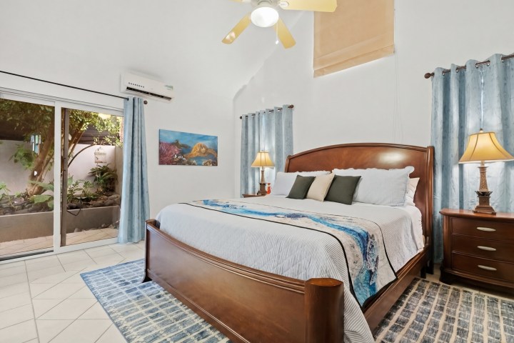 Cozy bedroom with wooden bed, lamps, and sliding door to garden.