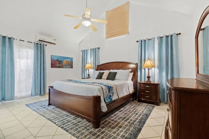 Cozy bedroom with wooden bed, blue curtains, and ceiling fan.