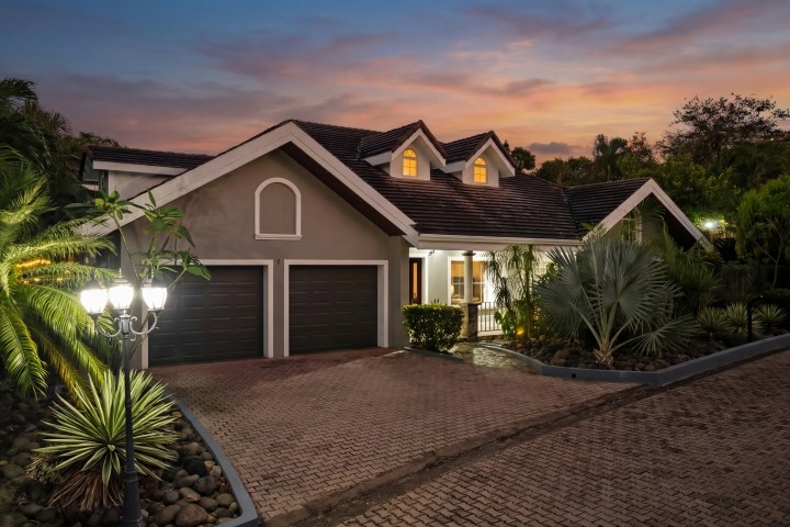 House with two garages and garden at sunset.