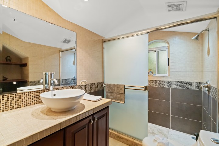 Modern bathroom with basin sink, mirror, glass shower, and towel rack.
