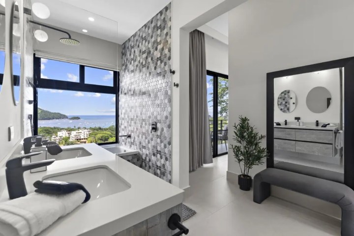 Modern bathroom with ocean view, dual sinks, gray accents, and large mirror.