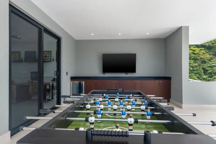 Modern room with foosball table, wall-mounted TV, and large window.