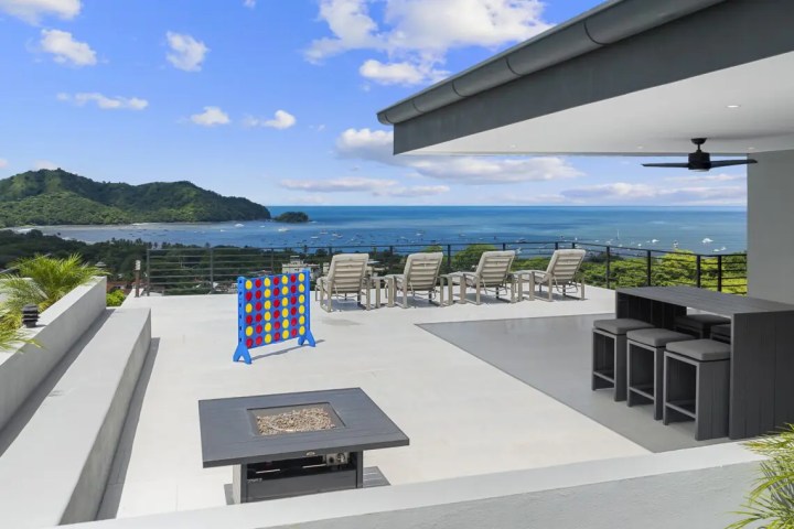 Rooftop patio with seating, sea view, and large Connect Four game.