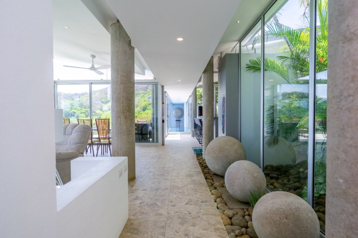 Modern hallway with large windows, stone spheres, and outdoor view.