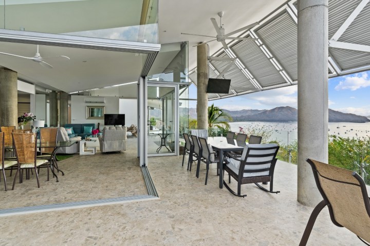 Open indoor-outdoor living space with ocean view, dining sets, and modern furnishings.