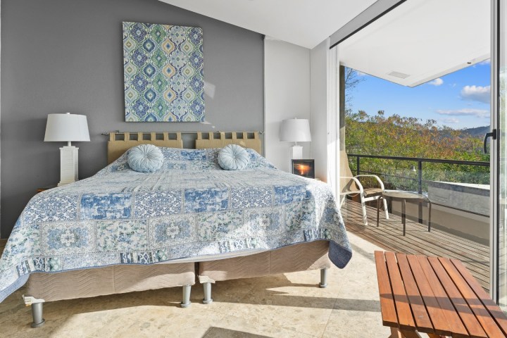 Bedroom with large bed, patterned quilt, artwork, and balcony view.